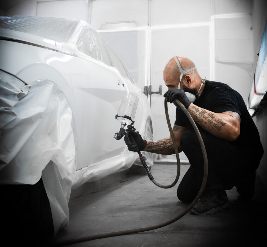 Technician performing Paintless Dent Repair on a car panel in Miami.