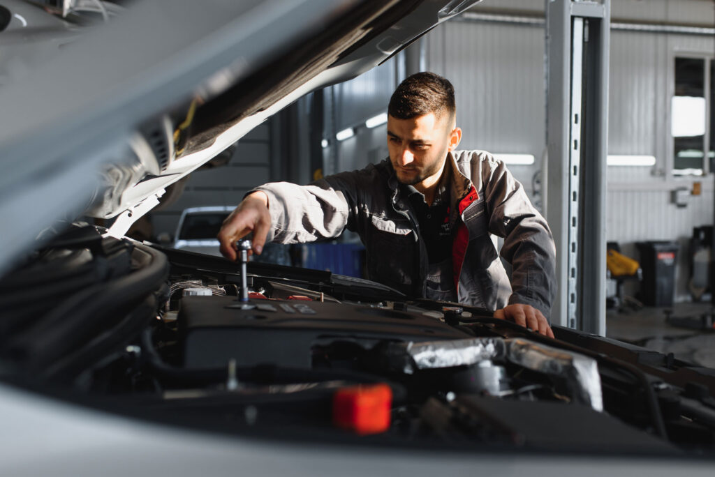 Auto technician working under the hood at a professional collision repair shop in Miami.