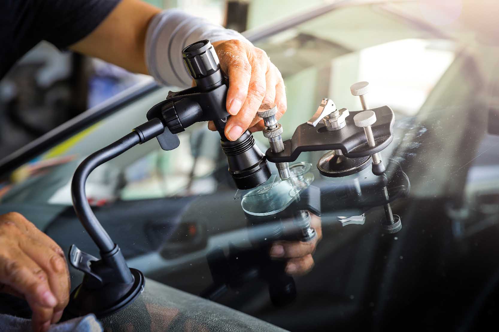 Scratched windshield glass being repaired by a professional using professional-grade equipment.